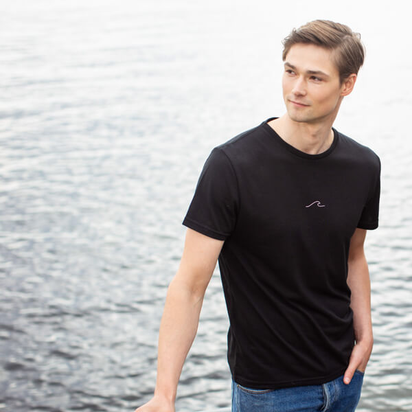 Man outside by the ocean in Eco Oceanness Midnight Black T-shirt