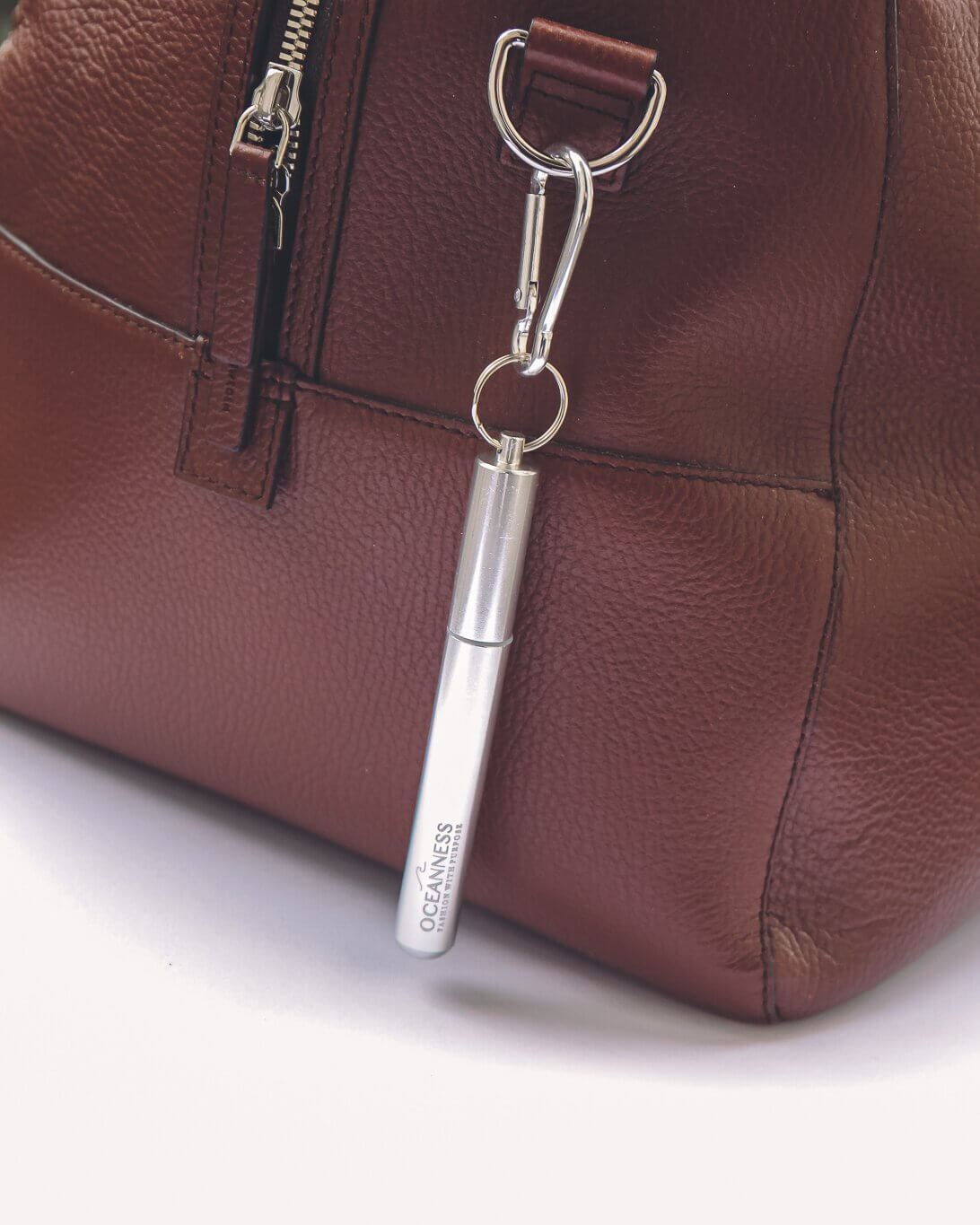 Oceanness silver reusable travel straw hanging on a bag with carabiner