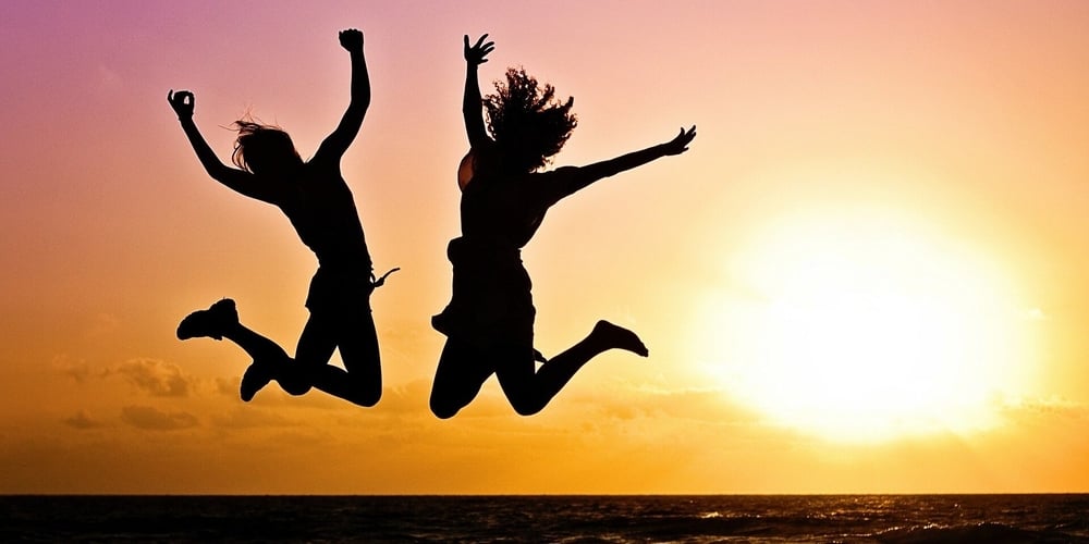 Happy people jumping on the beach in the sunset