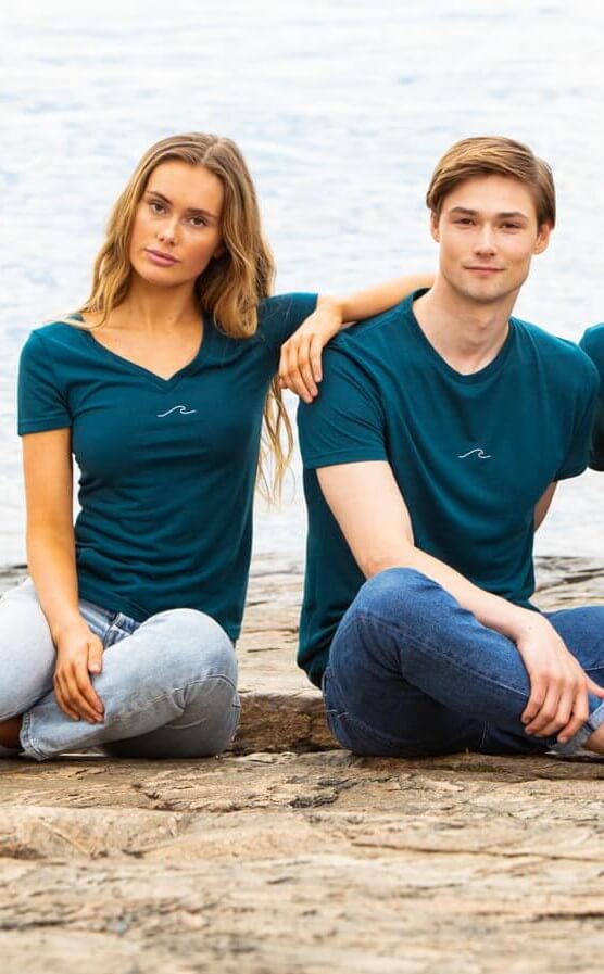 Man and woman in Oceanness t-shirt in Ocean Green by the ocean