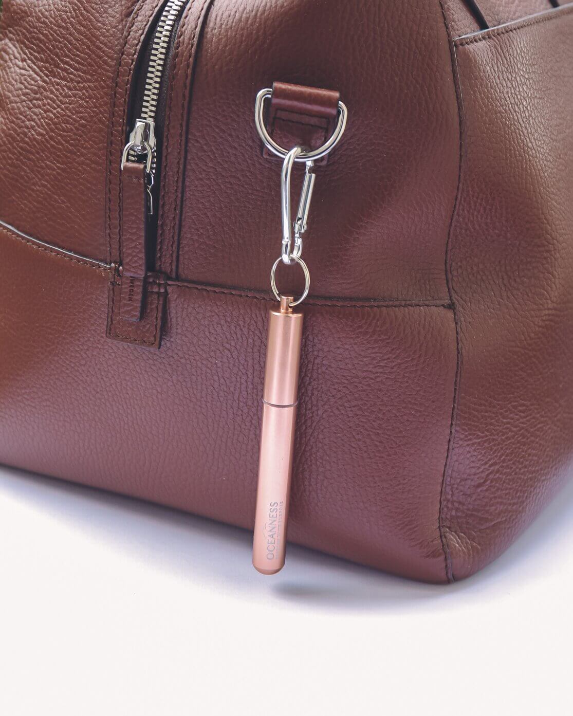 Oceanness rose gold reusable travel straw hanging on a bag with carabiner